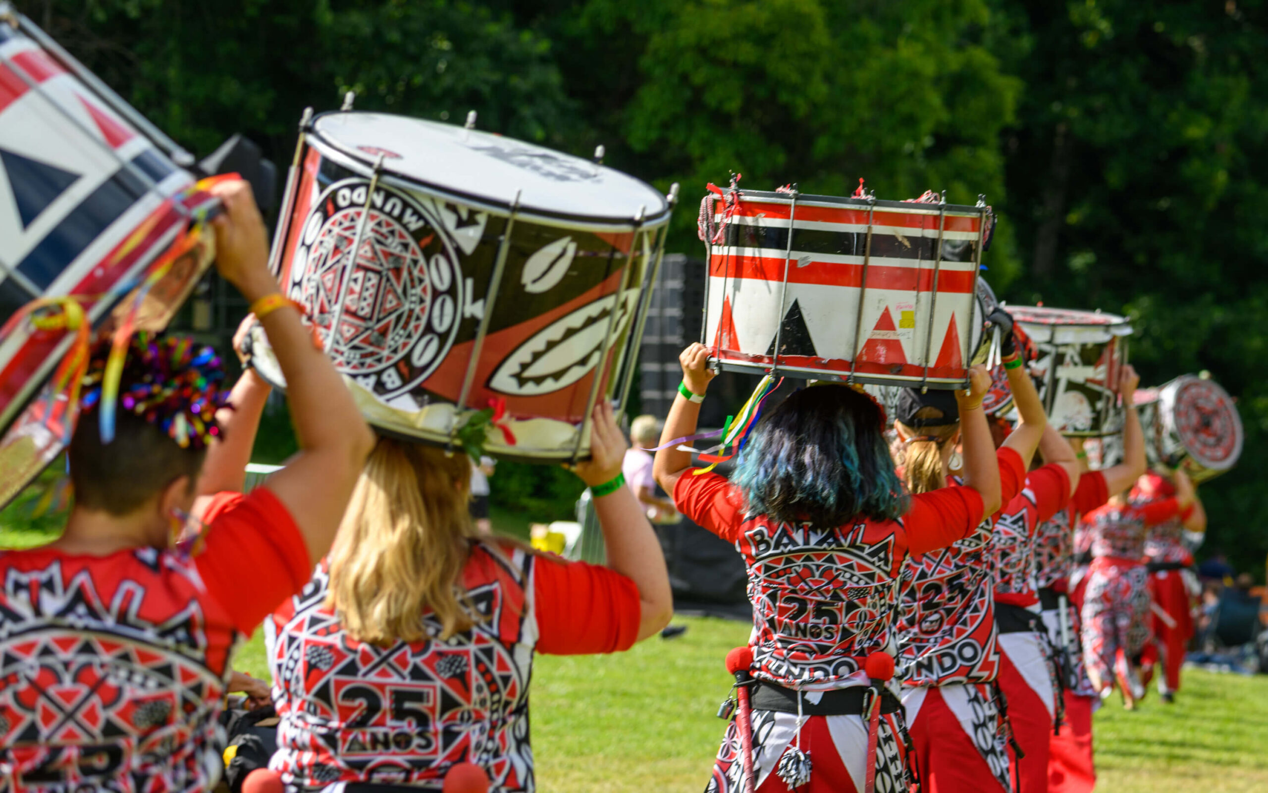 Batalá Washington DC band members walking through a park carrying their drums on their heads